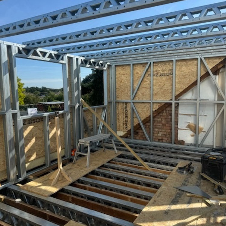 Loft conversion mid-way through construction, with exposed steel beams, and unfinished flooring.